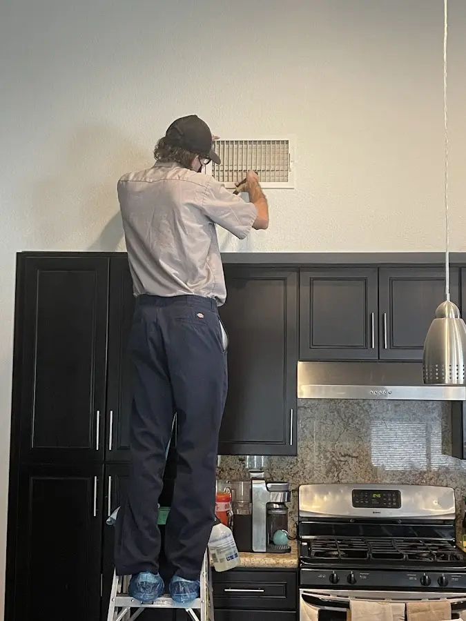 Technician inspecting an air vent during HVAC service in Cherokee Village
